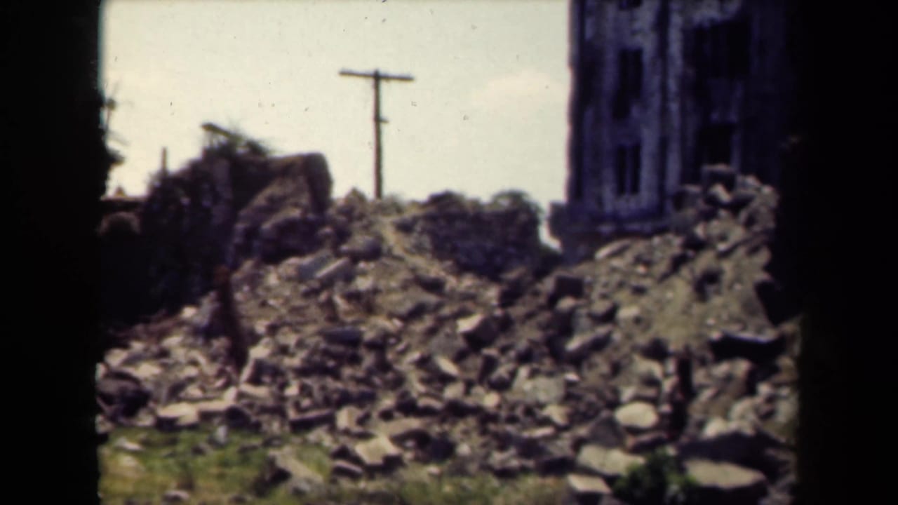 Similar view of rubble and ruined masonry with a utility pole in the background.