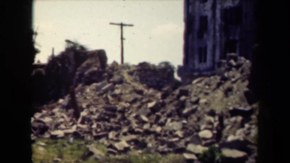 1940s Manila frame with damaged masonry, scattered rubble, and a utility pole visible behind the ruins.