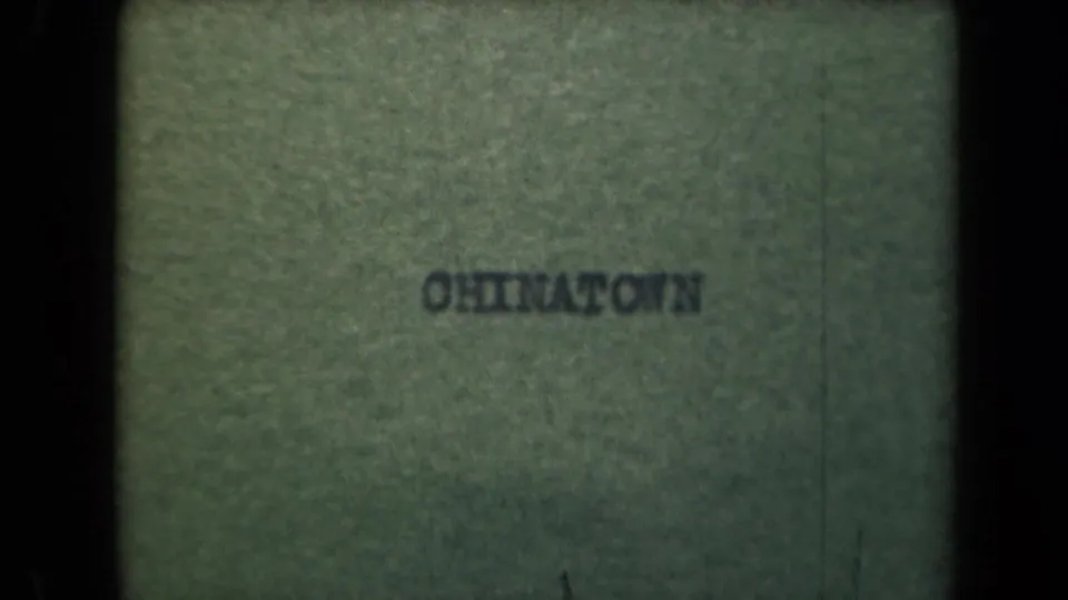Title card from the 8mm clip reading "CHINATOWN," with faded color and dark film borders.