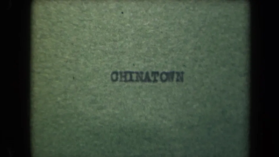 Faded 8mm title card reading "CHINATOWN," used as an in-camera location identifier for the Manila sequence.