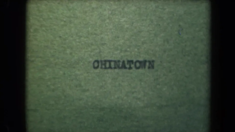 A greenish 8mm leader or edge frame with reversed text, heavy grain, and dark borders before the Manila street view begins.