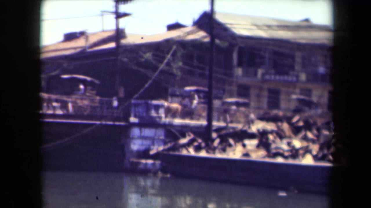 Boats and older buildings beside water, seen through soft 8mm film framing.