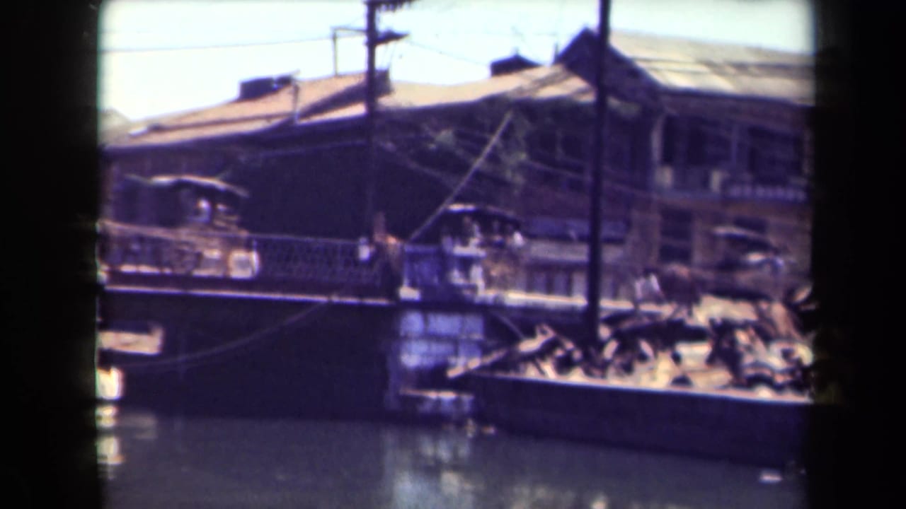 Waterfront buildings, boats, and poles viewed through dark film-strip borders.