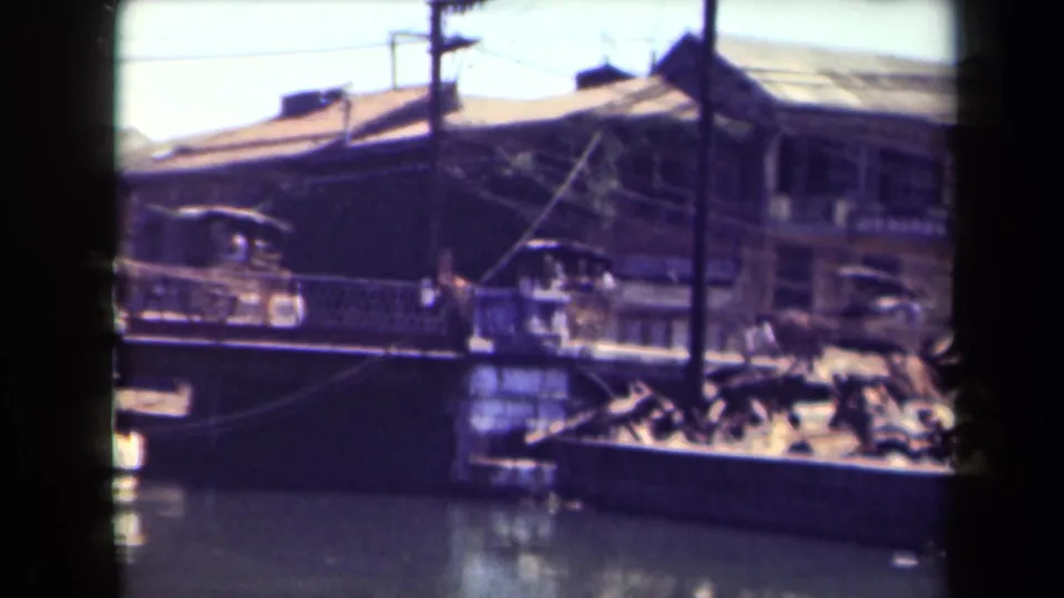 1940s Manila waterfront view with boats, older buildings, rooflines, and utility poles visible in faded 8mm color.