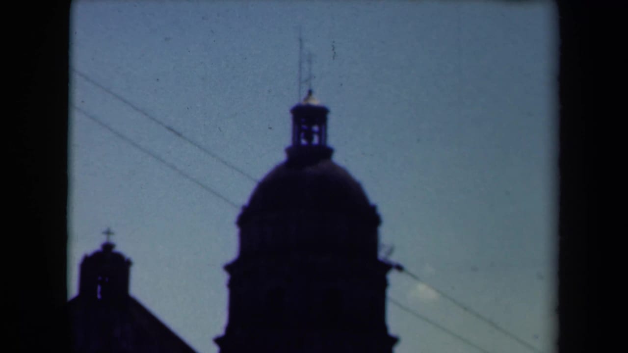 Silhouetted domed church tower and smaller tower framed against open sky.