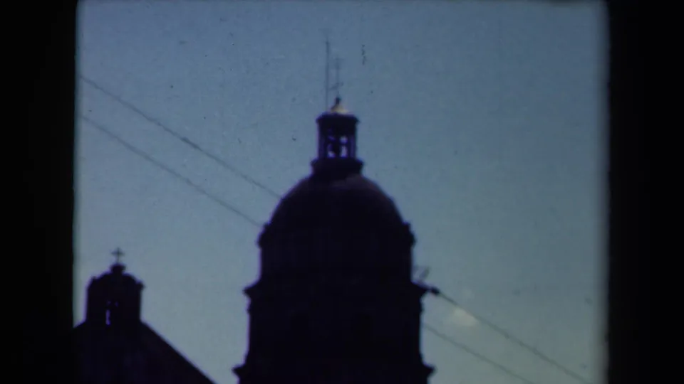 A visitor-shot view of a Manila church silhouette, with a large dome, smaller tower, and diagonal wires visible in the sky.
