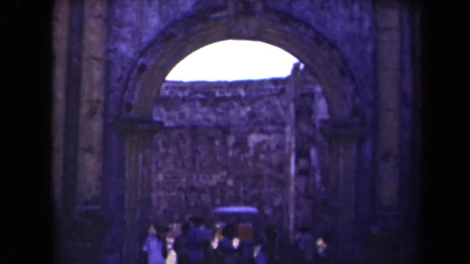 1940s Manila home-movie frame showing visitors near an arched ruin entrance and rough stone walls.