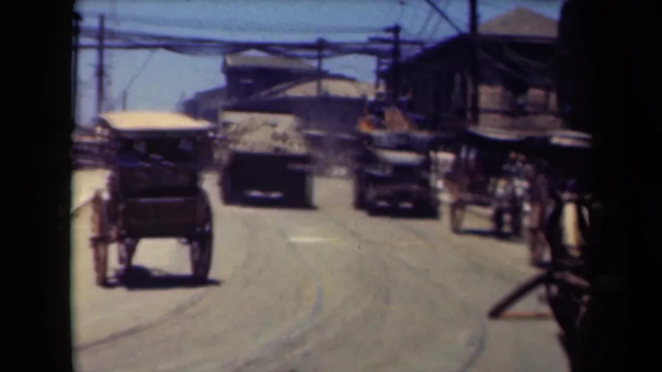 1940s Manila street scene with a horse-drawn buggy, boxy motor vehicles, pedestrians, overhead utility lines, and low roadside buildings.