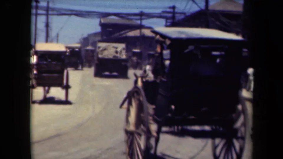 A dark horse-drawn carriage fills the foreground on a 1940s Manila street, with other buggies, motor vehicles, and pedestrians beyond.