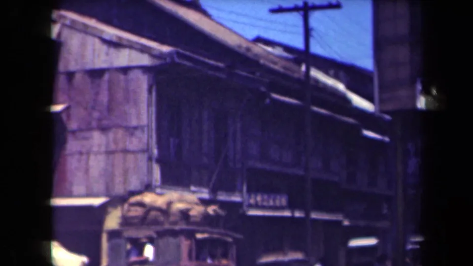 1944 Manila street-side view showing weathered wooden buildings, corrugated roofs, utility poles and wires.