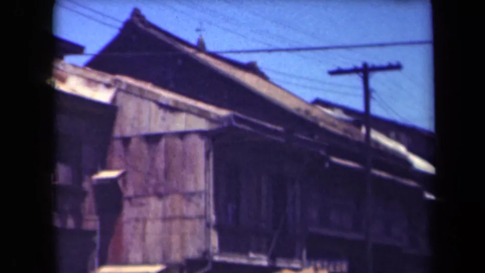 1944 Manila view of wooden street-front buildings, corrugated rooflines, utility wiring and bright sky.
