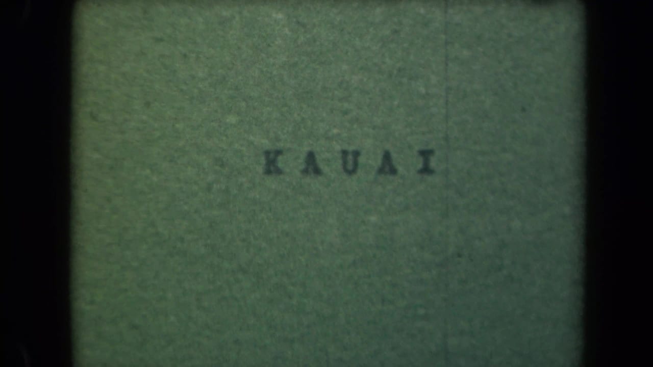 Green title card with the word KAUAI centered inside dark film borders.