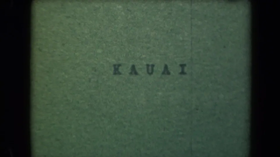A green 8mm title card reads KAUAI, suggesting a reel title or transition rather than the building view.