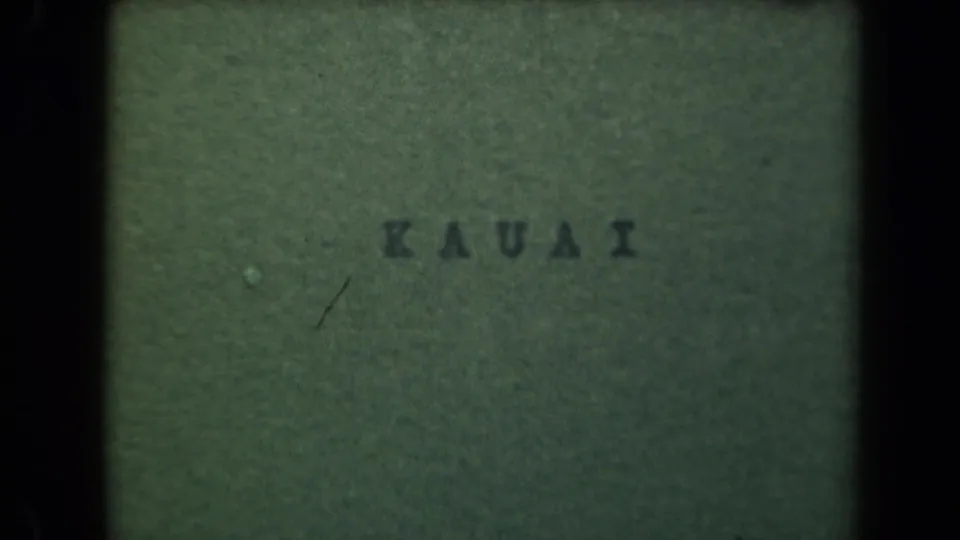 The final 8mm frame holds on the green KAUAI title card, with scratches, grain, and uneven exposure visible.