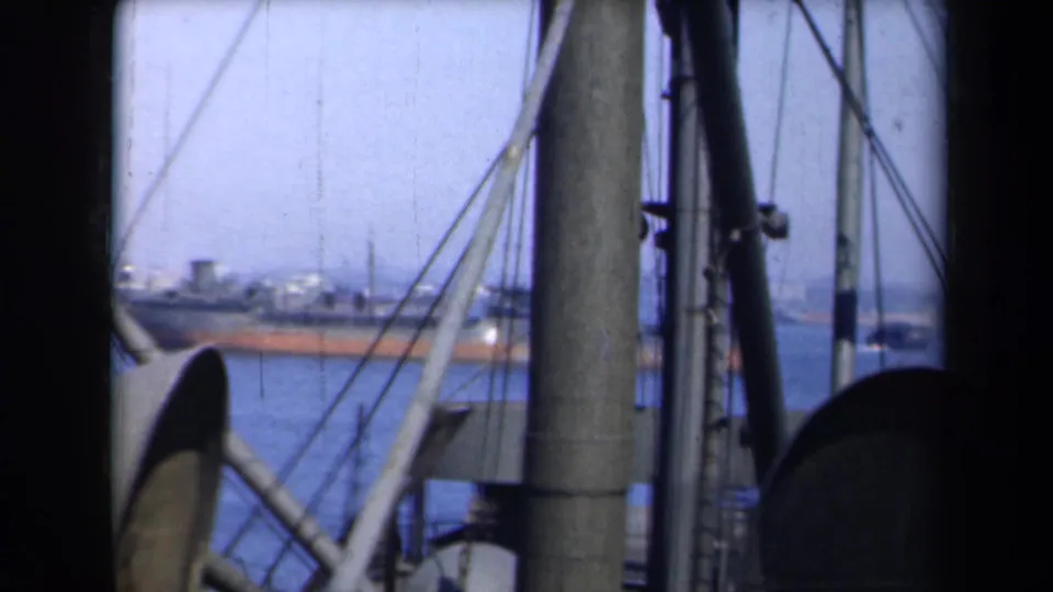 1946 New York harbor view through ship rigging, with a distant vessel crossing blue water.