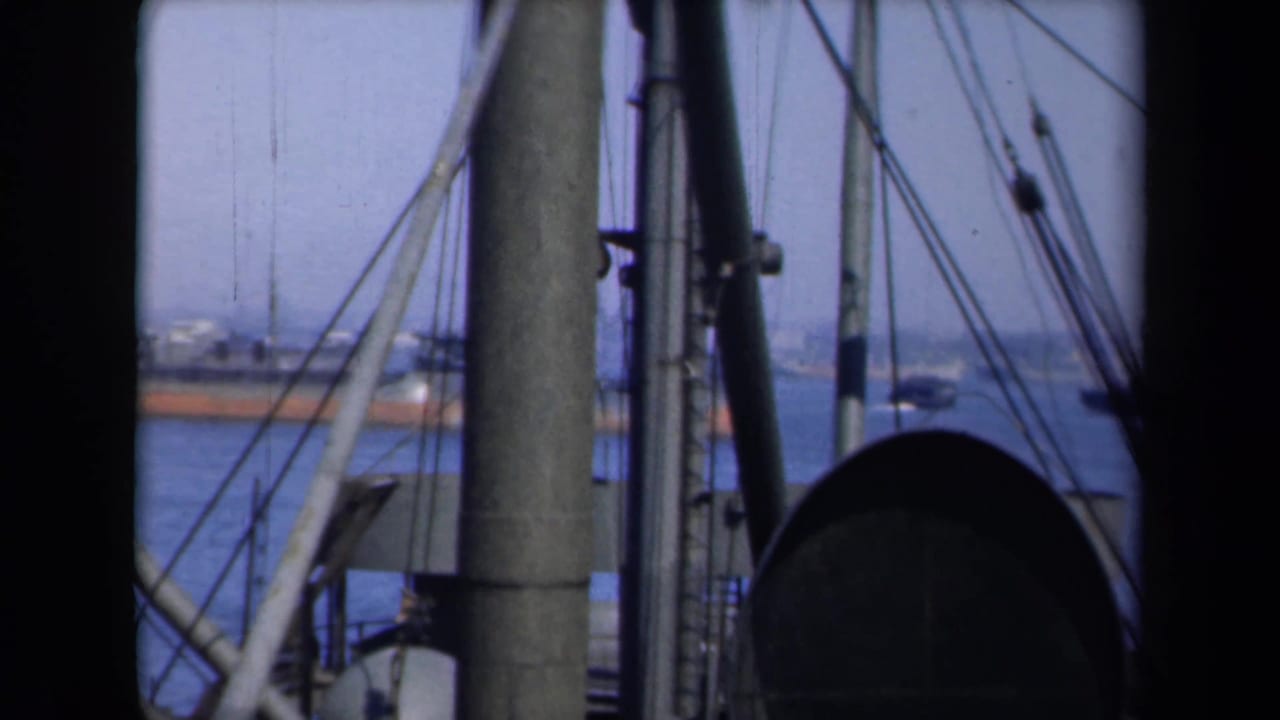Masts and lines frame distant ferry-like vessels across the water.
