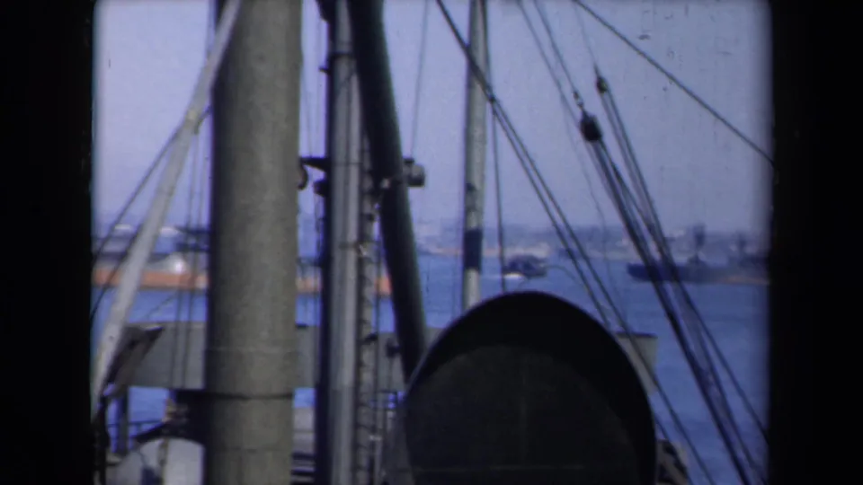 New York harbor scene with ship masts, rigging, blue water, and small distant boats from a 1946 home movie.