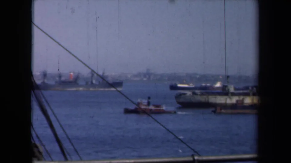 New York Harbor in 1946, showing a tugboat near a larger vessel and distant shoreline through ship rigging.