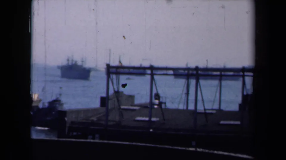 1946 New York harbor scene with a silhouetted pier structure in front, a large vessel offshore, and part of a tugboat at the frame edge.