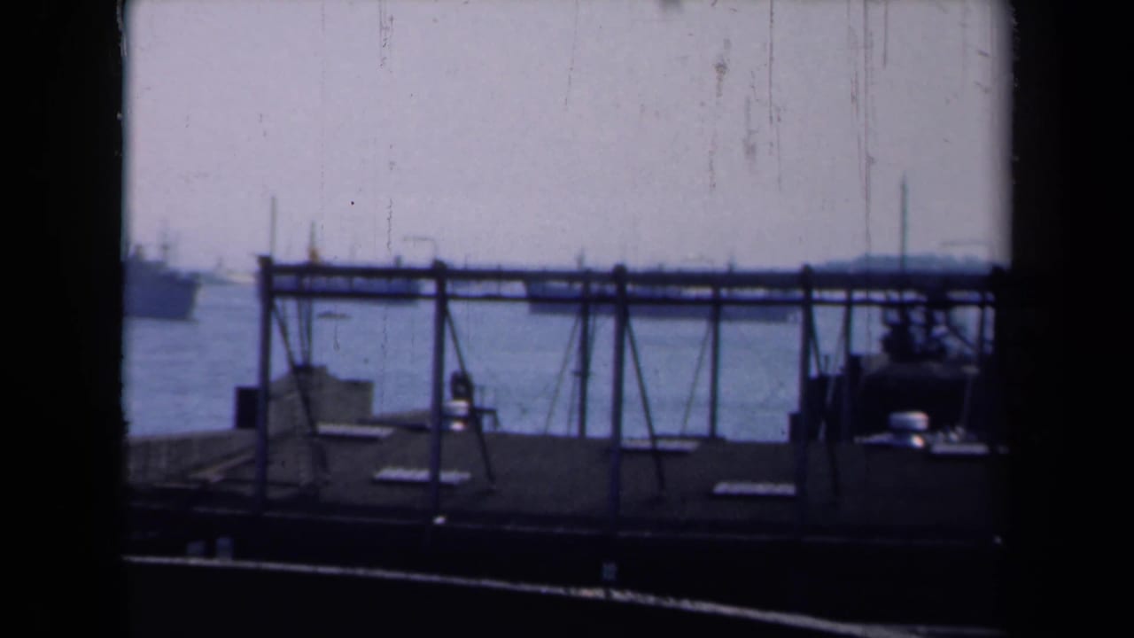 Harbor water with a dock rail structure and a large ship in the distance.