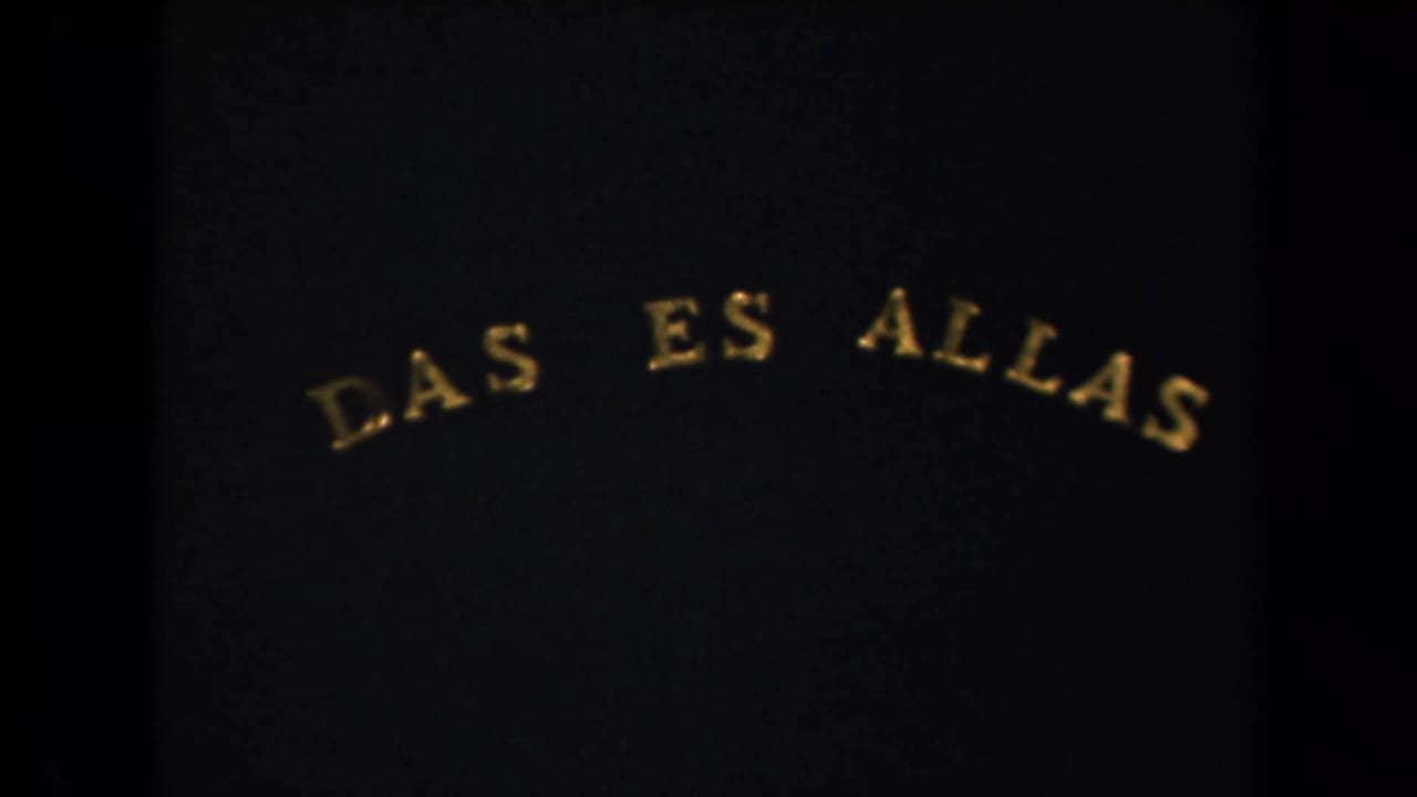 1940s 8mm frame from a New York-labeled reel showing a dark title card with arched gold lettering reading "DAS ES ALLAS."