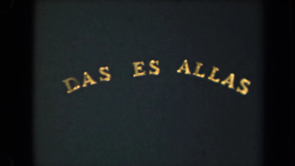 Dark 8mm title-card frame with gold arched text near the top and a muted green-blue cast from the scanned film.