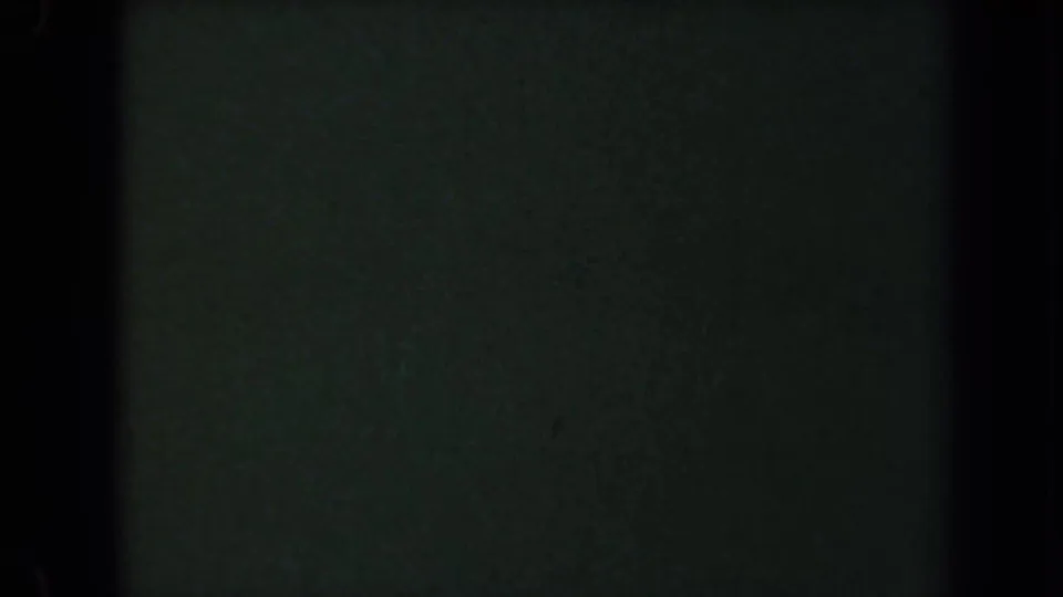 Final 8mm frame with a mostly blank dark green card surface, black borders, and visible grain, following the photographed title card.