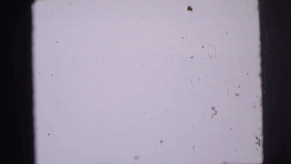 Overexposed pale film frame with dark 8mm borders and visible surface marks, without a clearly identifiable subject.