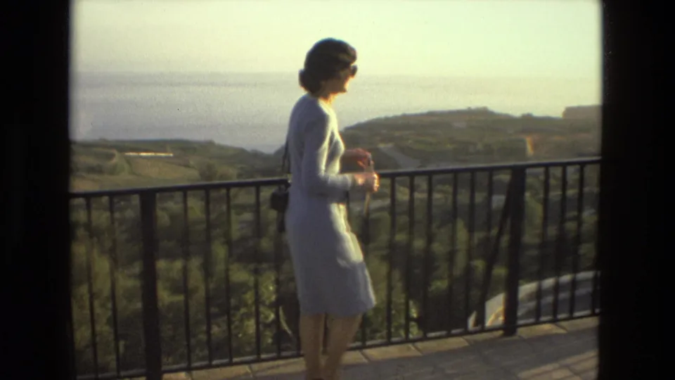 A 1978 Andalusia travel frame shows the woman near the railing, with sunlit hills, coastline, and terrace shadows visible.