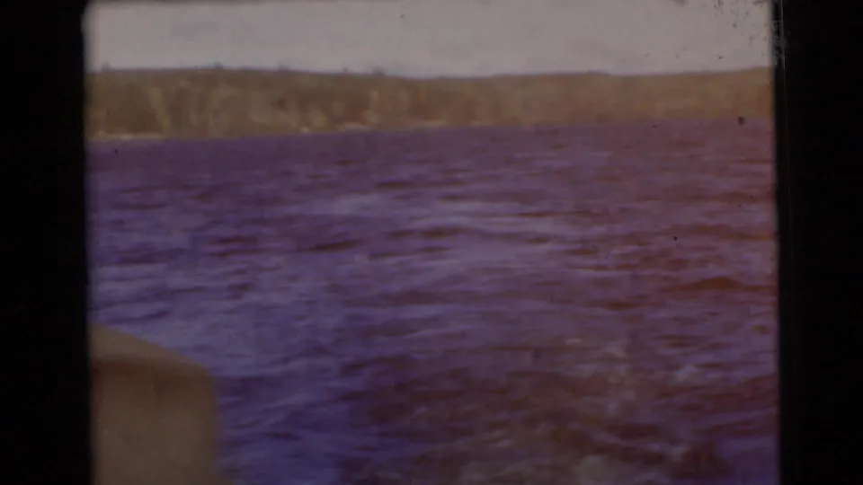 Faded-color 1956 8mm view of Traverse City-area water, with purplish tones and a low tree-lined shore.