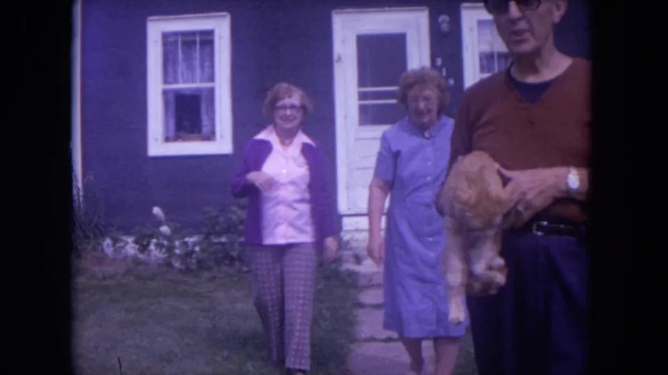 The group nears the camera in the Chicago yard, with the man partly cropped at right while holding the orange tabby cat.