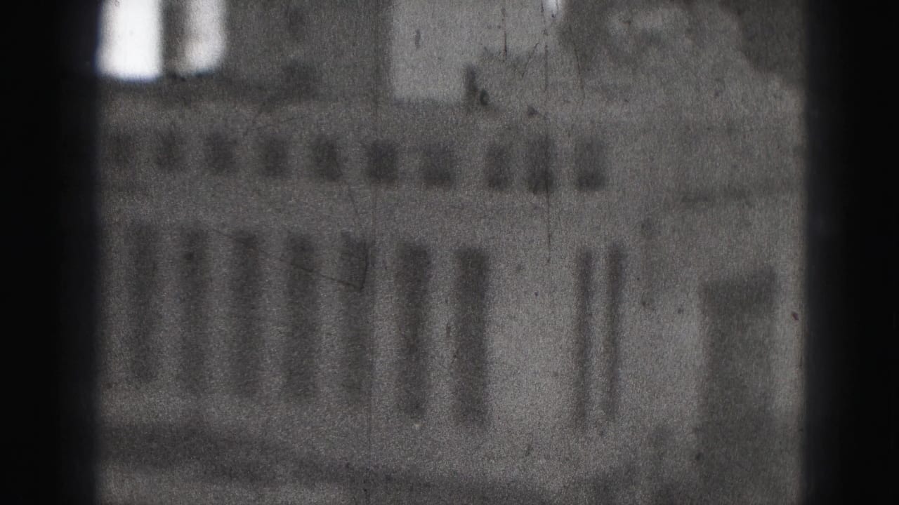 Blurred 1946 Harrisburg 8mm frame showing a large urban building facade with rows of windows and heavy film grain.