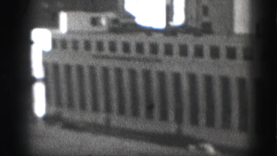 Grainy 1946 Harrisburg frame showing a large building front, repetitive windows, bright edge highlights, and handheld softness.
