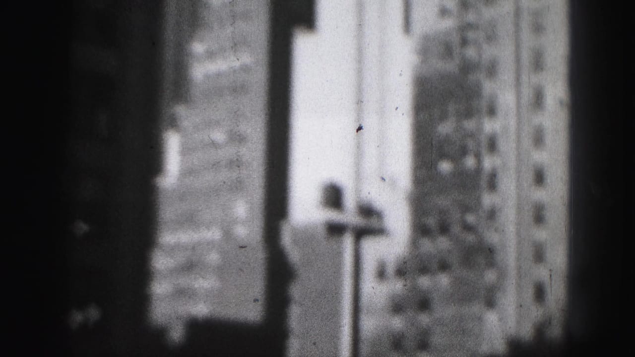 Blurred tall building facade with a streetlamp near the right side of the frame.