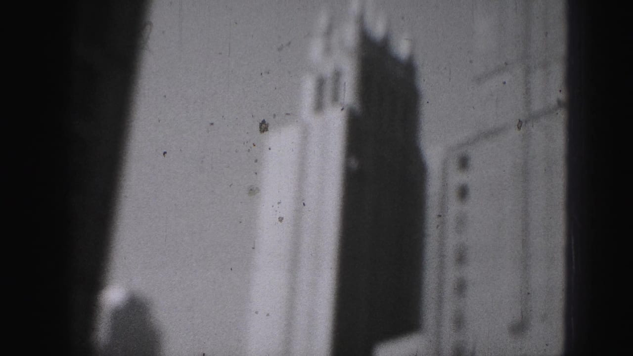 1946 Harrisburg 8mm frame showing blurred tall urban facades and deep shadow from an elevated city vantage.