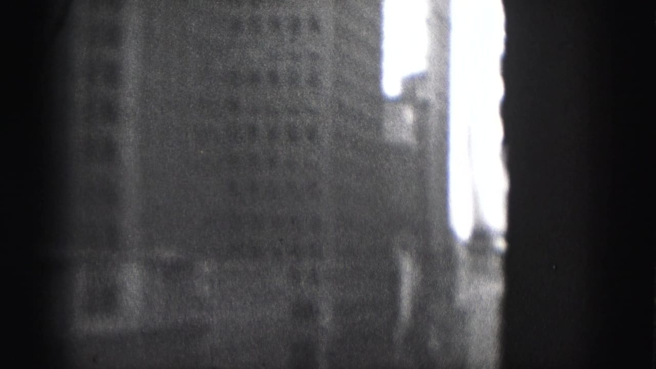 Blurred black-and-white urban building facade partly blocked by a dark vertical edge.