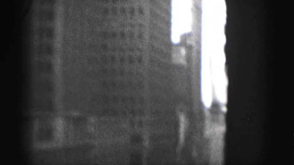 1946 Harrisburg home-movie frame with a tall building wall and bright window openings partly obscured by dark framing.