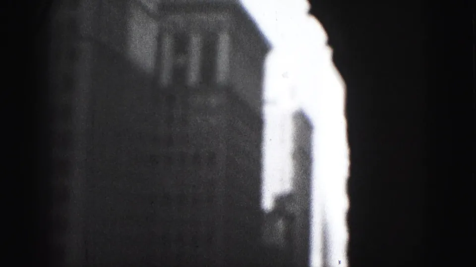 Grainy 1946 Harrisburg frame showing a bright building edge, dark urban facade, and partial street detail in heavy contrast.