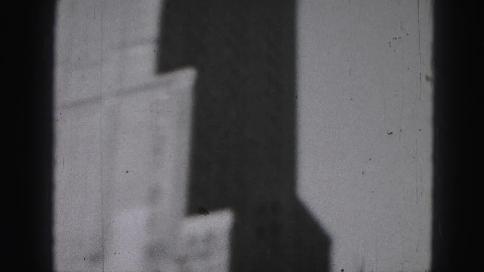 1946 Harrisburg 8mm frame showing a soft-focus building facade, dark foreground edge, bright sky, and visible film scratches.