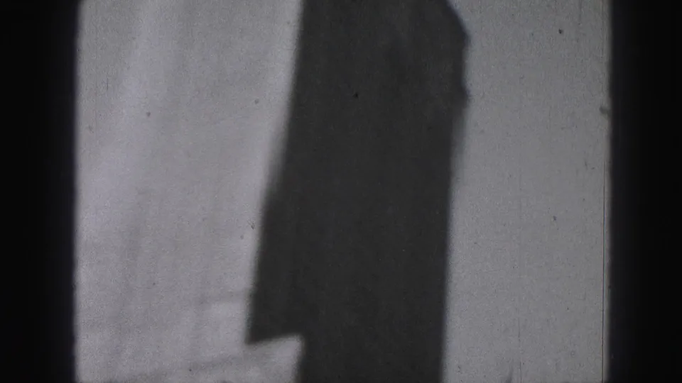 1946 Harrisburg home-movie frame showing a tall dark building profile against pale sky with scratches and grain.