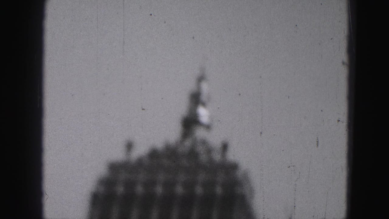Blurred domed building seen through dark vertical window framing.