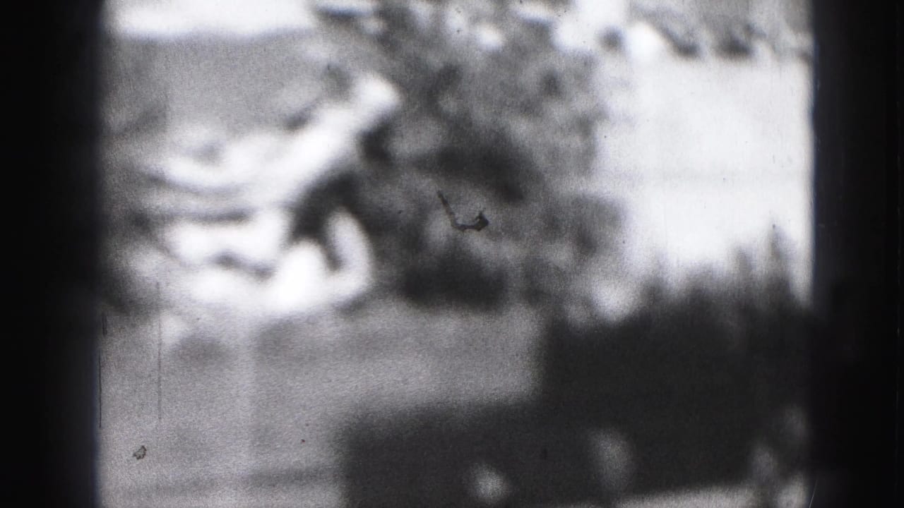 1946 Harrisburg home-movie frame with indistinct people skating or standing near a rink, softened by grain and exposure haze.