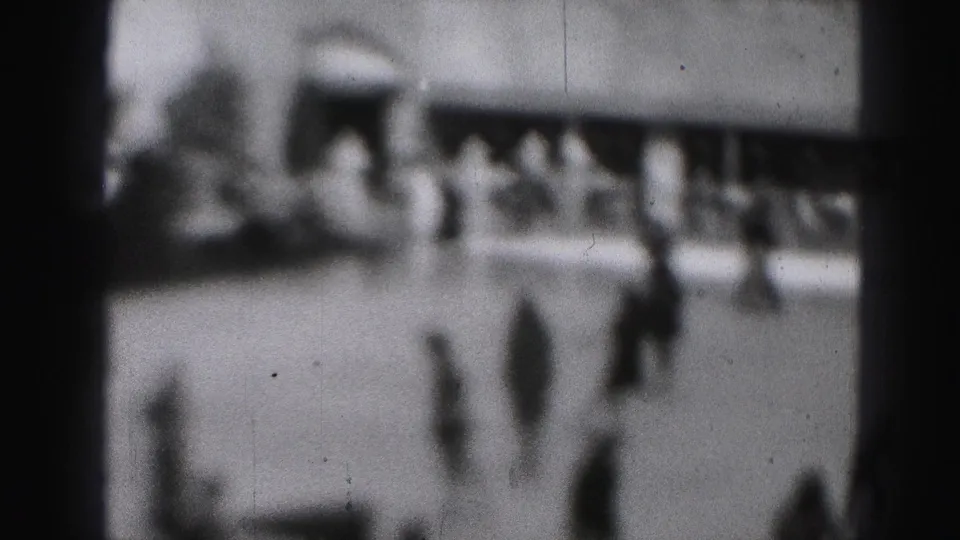 Black-and-white 8mm view of the 1946 Harrisburg rink with multiple indistinct people skating or standing near the ice.