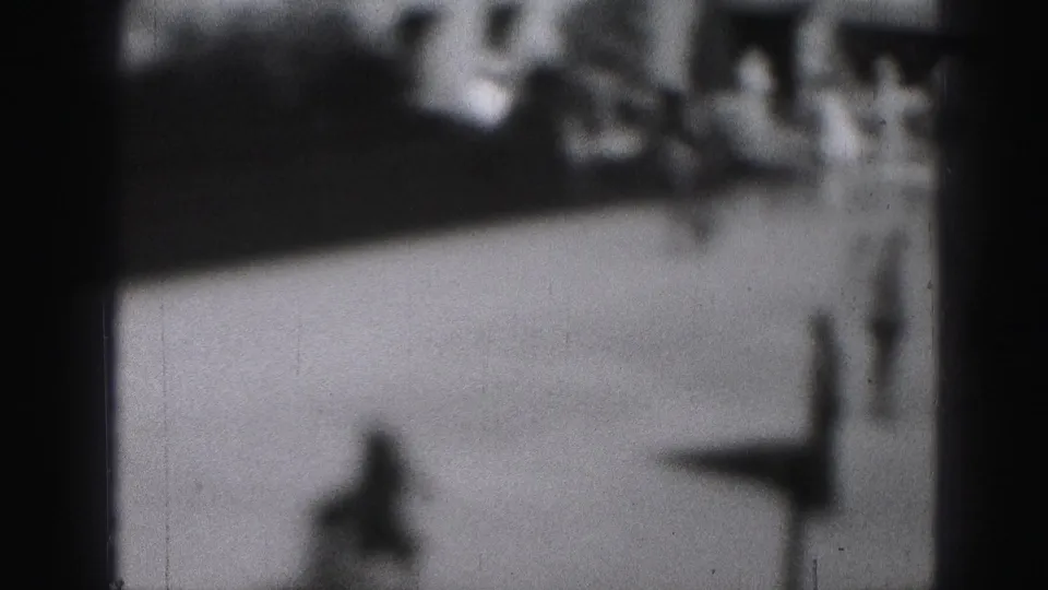 Soft 8mm frame from Harrisburg, 1946, with a lone skater shape crossing the ice and spectators beyond.