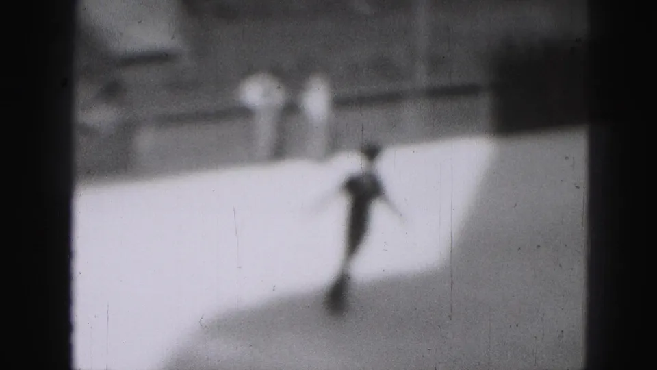 Blurred black-and-white home-movie frame showing a skater on bright ice in Harrisburg, Pennsylvania, in 1946.