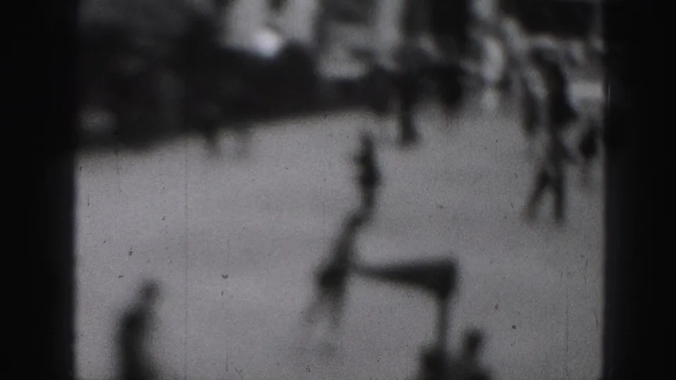 Soft, abstract 8mm frame from the Harrisburg clip with blurred foreground shapes and heavy black-and-white grain.