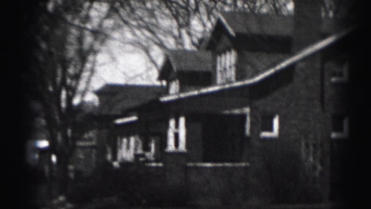 Two-story house with porch, gabled roof, bare trees, and dark film border.