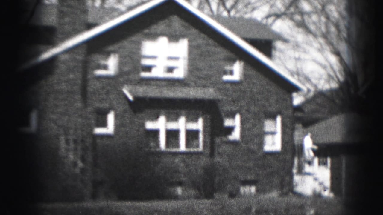 1946 Harrisburg home-movie frame showing a two-story brick house with white-trim windows and bare branches in the background.