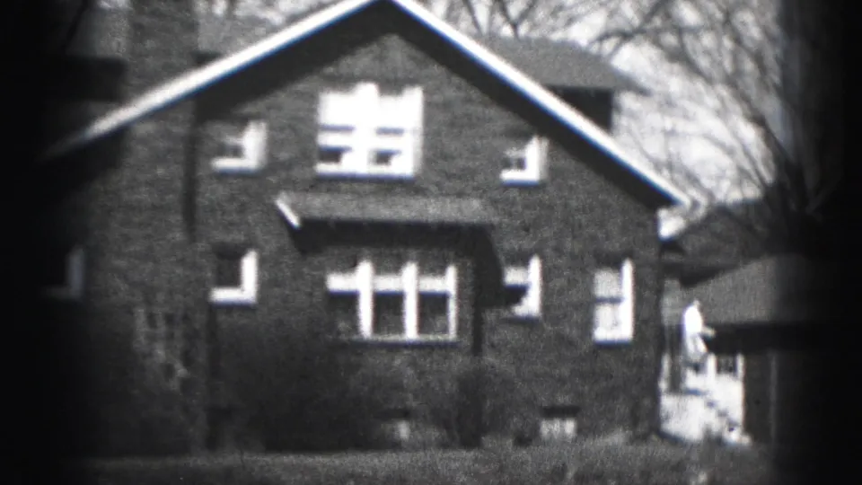 1946 Harrisburg home-movie frame showing a two-story brick house with white-trim windows and bare branches in the background.