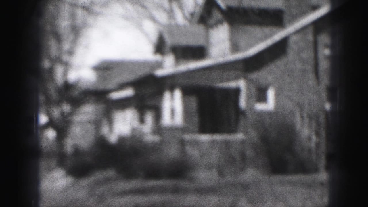 1946 Harrisburg home-movie frame showing a modest house exterior, porch, yard, and bare trees in soft 8mm focus.